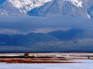 Ice fisherman sitting on a frozen flathead lake with snow covered mountain in the background 