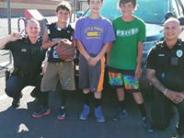 Police officers pose with children in front of a police car holding a basketball