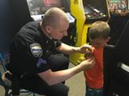 Police officer pinning a badge to a young boys shirt at a local arcade