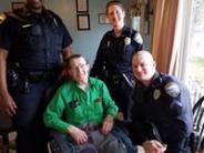 Police officers posing with a local elderly man in his home