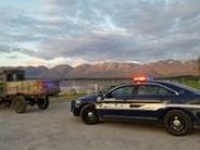 Police vehicle with its lights on behind an older truck with the mountain range in the background 