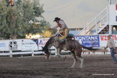 Cowboy riding in the saddle bronc riding competition in the local rodeo