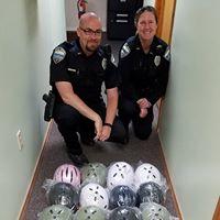 2 Police officers kneeling next to new bicycle helmets for the local youth