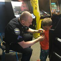 Police officer pinning a badge to a young boys shirt at a local arcade