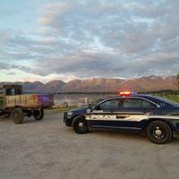 Police vehicle with its lights on behind an older truck with the mountain range in the background 
